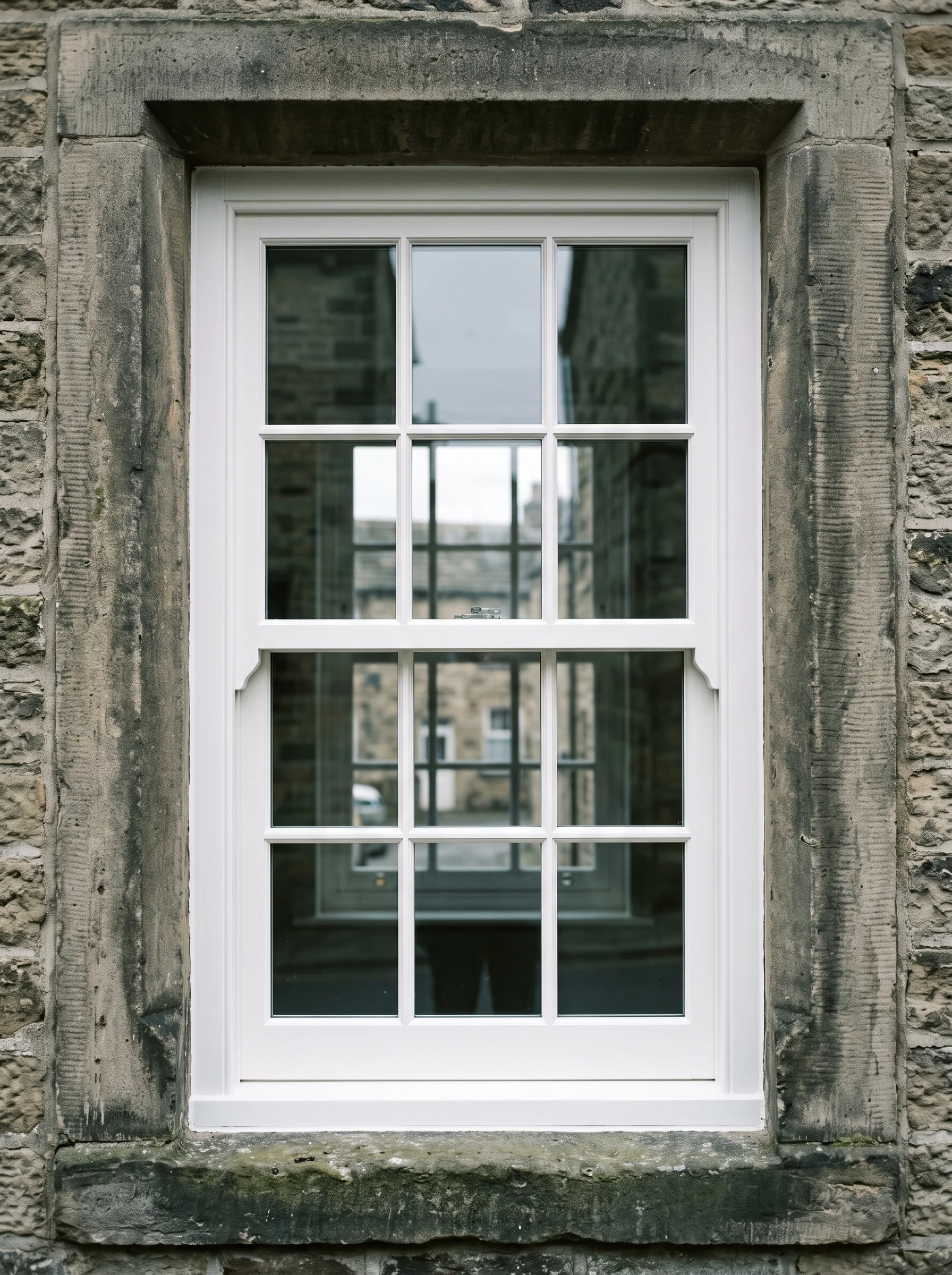 A restored Georgian box sash window with six-over-six glazing bars in a millstone-grit reveal